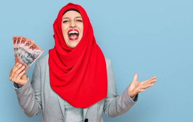 İslami tesettüre bürünmüş güzel İspanyol bir kadın elinde Avustralya dolarlarıyla zaferi kutlayan banknotlar mutlu bir gülümsemeyle ve ellerini kaldırarak kazanan bir ifadeyle. 