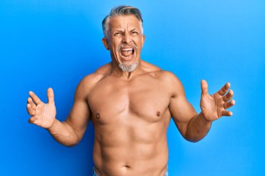 Orta yaşlı, kır saçlı, üstsüz, deli deli deli dikilmiş agresif bir ifade ve kollarla bağıran bir adam. hüsran kavramı. 