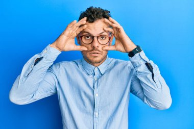 Gündelik kıyafetler ve gözlük takan genç İspanyol adam gözlerini parmaklarıyla açmaya çalışıyor, uykulu ve yorgun bir şekilde sabah yorgunluğu çekiyor. 