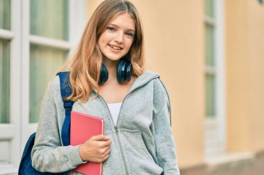 Güzel beyaz öğrenci şehirde kulaklık kullanıyor..