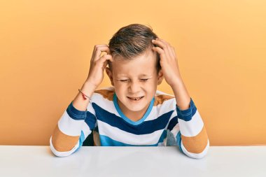Kafkasyalı sevimli bir çocuk. Masada oturmuş acı ve migrenden dolayı baş ağrısı ve stresten muzdarip. Eller başının üstünde.. 