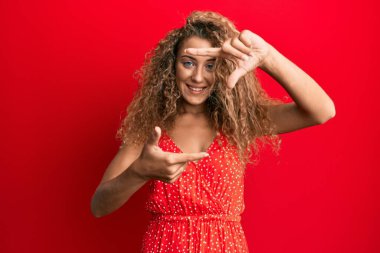 Yazlık elbise giymiş, gülümseyen, elleri ve parmakları mutlu yüzlü güzel beyaz bir kız. yaratıcılık ve fotoğrafçılık kavramı. 