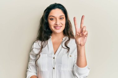 Beautiful middle eastern woman wearing casual clothes showing and pointing up with fingers number two while smiling confident and happy. 
