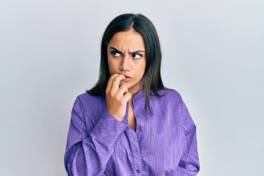 Genç esmer kadın gündelik kıyafetler giyiyor. Stresli ve gergin görünüyor. Ağzı tırnak yiyen ellerle. anksiyete. 