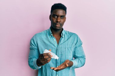 El dezenfektanı jeli kullanan yakışıklı siyahi adam yüzünde ciddi bir ifadeyle rahatlamış. Basit ve doğal bir şekilde kameraya bakıyorsun.. 