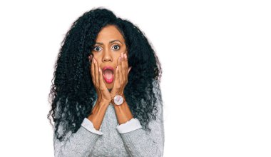 Orta yaşlı Afro-Amerikalı kadın günlük giysiler giyiyor korkmuş ve şok olmuş, şaşırmış ve şaşırmış bir halde. 