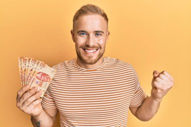 Meksika pezosu tutan genç beyaz adam gururla bağırıyor zaferi ve başarıyı kutluyor. 