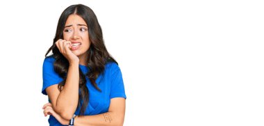 Güzel, esmer, gündelik kıyafetler giyen, gergin ve elleri ağızdan tırnak yiyen genç bir kadın. anksiyete. 