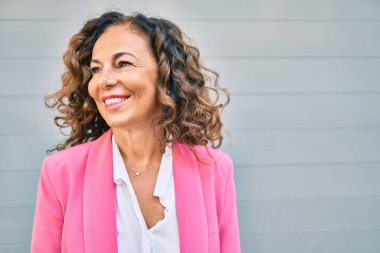 Orta yaşlı İspanyol iş kadını şehirde mutlu bir şekilde ayakta duruyor..