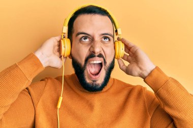 Sakallı genç adam kulaklık takıp müzik dinliyor. Öfkeli ve öfkeli çığlıklar atıyor. Öfkeyle bağırıyor.. 