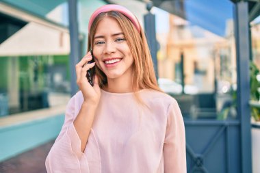 Beyaz kız gülümsüyor. Şehirdeki akıllı telefondan konuşuyor..