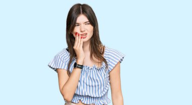 Genç, beyaz, günlük kıyafetler giyen, diş ağrısı ya da diş hastalığından dolayı ağızlarına acı dolu bir ifadeyle dokunan genç bir kız. dişçi 