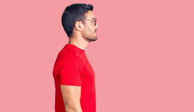 Gündelik kıyafetler ve gözlük takan genç İspanyol adam yan yan yan bakıyor, rahat poz veriyor kendine güvenen bir gülümsemeyle doğal bir yüz ifadesi sergiliyor.. 