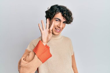 Latin kökenli genç adam, sıradan bir kazak giyiyor ve parmaklarıyla dört numarayı gösterip gülümserken kendinden emin ve mutlu. 