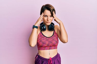 Kısa saçlı, esmer, spor giyimli, kulaklık takan, başı ağrıyan bir kadın. Stres yüzünden. migren ağrısı. 