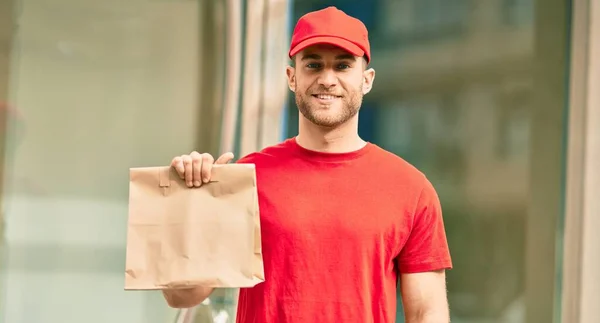 年轻的高加索送货员带着纸袋在城里高兴地微笑着 — 图库照片