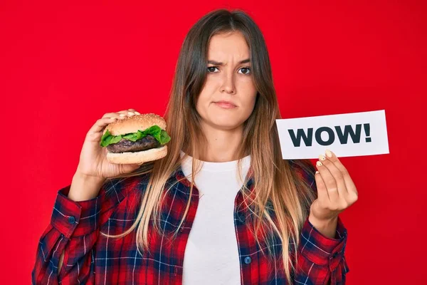 Beautiful Caucasian Woman Eating Tasty Classic Burger Holding Wow Text — Stock Photo, Image