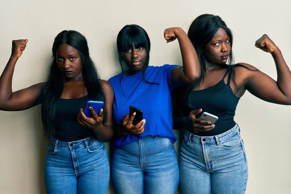 腕の筋肉を示すスマートフォンの強い人を使用して3人の若いアフリカ系アメリカ人の友人 自信と力の誇り — ストック写真