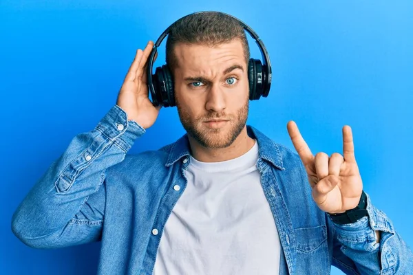 Young Caucasian Man Using Headphones Doing Rock Symbol Skeptic Nervous — Stock Photo, Image