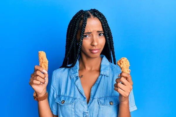 Beautiful Hispanic Woman Eating Chicken Wings Skeptic Nervous Frowning Upset — Stock fotografie