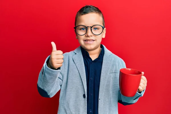 Mały Chłopiec Okularach Pijący Czerwonego Kubka Uśmiechnięty Szczęśliwy Pozytywny Kciuk — Zdjęcie stockowe