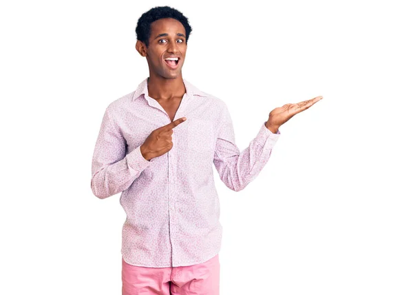 手で提示し 指で指している間 アフリカのハンサムな男は カジュアルなピンクのシャツを身に着けている驚きとカメラに笑顔 — ストック写真