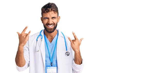 穿着医生制服和听诊器的年轻人带着疯狂的表情大喊着举起双手做摇滚符号 音乐明星 沉重的概念 — 图库照片