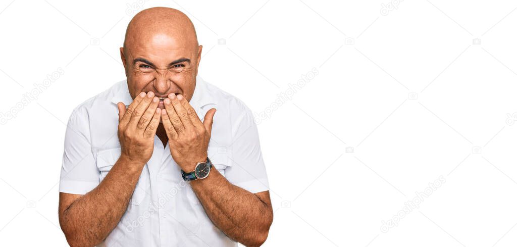 Mature middle east man with mustache wearing casual white shirt laughing and embarrassed giggle covering mouth with hands, gossip and scandal concept 