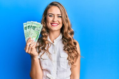 10.000 Güney Koreli genç sarışın kız para kazandı. Pozitif görünüyor ve mutlu görünüyor. Kendine güvenen bir gülümsemeyle dişlerini gösteriyor. 