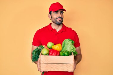 Yakışıklı, sakallı, üniformalı, elinde teslimat yemeği tutan, gülümseyen ve düşüncelere dalan bir İspanyol.. 