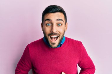 Gündelik kıyafetler giyen genç İspanyol adam gülümseyerek kahkahalarla gülüyor çünkü elleri vücutta olan komik, çılgın bir şaka.. 