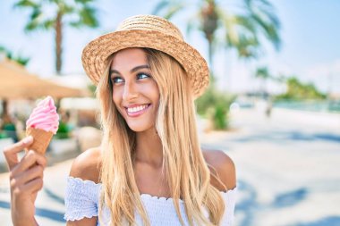 Genç sarışın turist kız gülümseyerek şehirde dondurma yiyor..