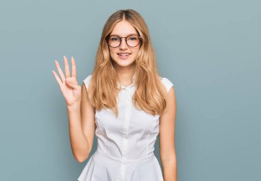 Güzel, genç, beyaz bir kız günlük kıyafetler ve gözlük takıyor. Dört numarayı gösteriyor ve işaret ediyor. Kendinden emin ve mutlu bir şekilde gülümsüyor.. 