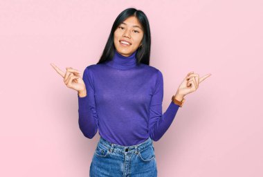 Güzel, genç Asyalı kadın gündelik kıyafetler giyip gülümsüyor ve farklı yönleri işaret ediyor. reklam için kopyalama alanı 