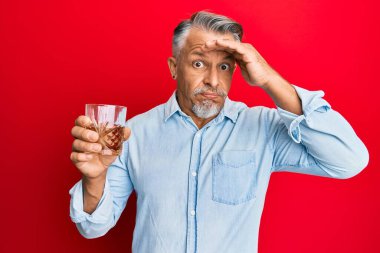 Orta yaşlı, kır saçlı, bir bardak viski içen, kafası karışmış, şaşırmış ve sinirli bir adam. 