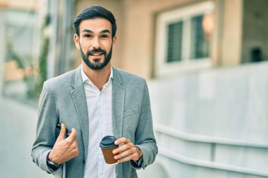 Genç İspanyol işadamı mutlu bir şekilde gülümsüyor, şehirde kahve içiyor..