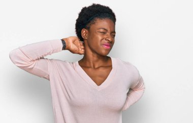 Genç Afro-Amerikan kız günlük kıyafetler giyiyor boynu ağrıyor, eli boynuna dokunuyor, kasları ağrıyor. 