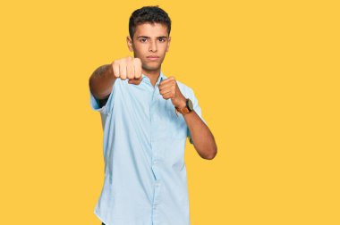 Genç, yakışıklı, Afro-Amerikalı, günlük kıyafetler giymiş, dövüşmek için yumruklarını yumrukluyor, agresif ve öfkeli, tehdit ve şiddet dolu. 