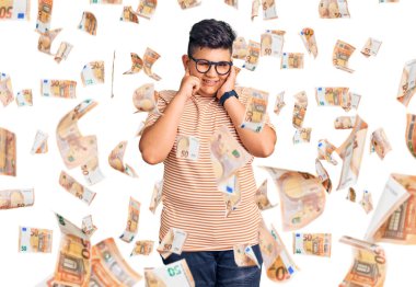 Gürültülü müzik sesi için günlük kıyafetler ve gözlük takan küçük çocuk kulaklarını parmaklarıyla kapatıyor. sağır kavramı.