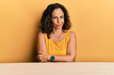 Masada sıradan kıyafetler giyen, kuşkucu ve gergin, yüzünde çapraz kollu tasvip etmeyen orta yaşlı güzel bir kadın. negatif kişi. 