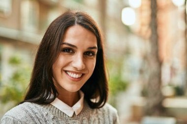 Genç İspanyol kadın gülümseyerek şehirde mutlu mesut dikiliyor..