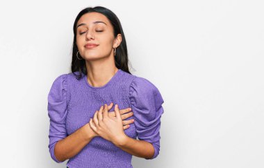 Gündelik kıyafetler giyen genç İspanyol kız elleri göğsünde, gözleri kapalı ve yüzünde minnet dolu bir jest ile gülümsüyor. sağlık kavramı. 