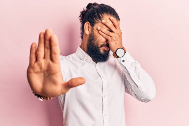 Genç Arap adam gündelik giysiler giyip elleri ile gözleri kapatıyor ve üzgün ve korku ifadeleriyle jest yapıyor. utangaç ve olumsuz kavram. 