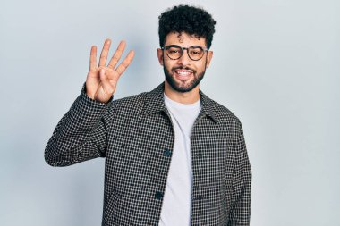 Sakallı, gözlüklü, dört numaralı parmaklarıyla işaret eden, kendinden emin ve mutlu gülümseyen genç bir Arap.. 