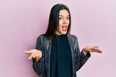 Parti ceketi giyen, elleri ve kolları havada, kafası karışmış genç İspanyol kız. şüphe kavramı. 