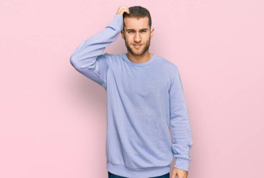 Günlük giysiler giyen genç beyaz bir adam soru sorup kafasını karıştırıyor. Şüpheyle kararsız, kafa kafaya düşünerek. Düşünceli kavram. 