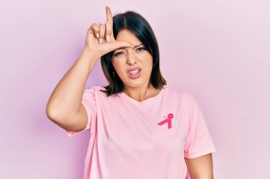 Tişörtüne pembe kanser kurdelesi takmış genç İspanyol kadın. Alnında parmakları olan insanlarla dalga geçiyor. Ezik hareketler yapıyor, alay ediyor.. 