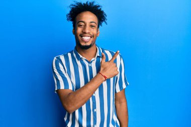 Sakallı, sıradan çizgili tişörtlü, gülümseyen, elleri ve parmaklarıyla yüzünü gösteren, mutlu ve doğal bir ifade takınan Afro-Amerikan genç adam. 