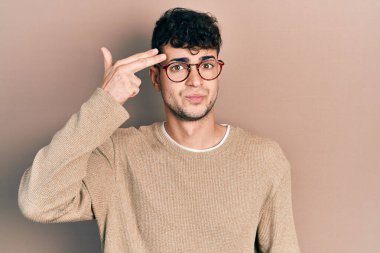 Gündelik giysiler giymiş, gözlüklü genç bir İspanyol adam kendini vuruyor ve öldürüyor. Silah gibi el ve parmakları işaret ediyor. İntihar hareketi.. 