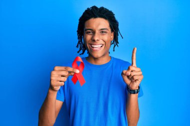 Genç Afrikalı Amerikalı adam elinde kırmızı kurdele ile gülümsüyor bir fikir veya soru işareti ile mutlu bir yüzle, bir numara 